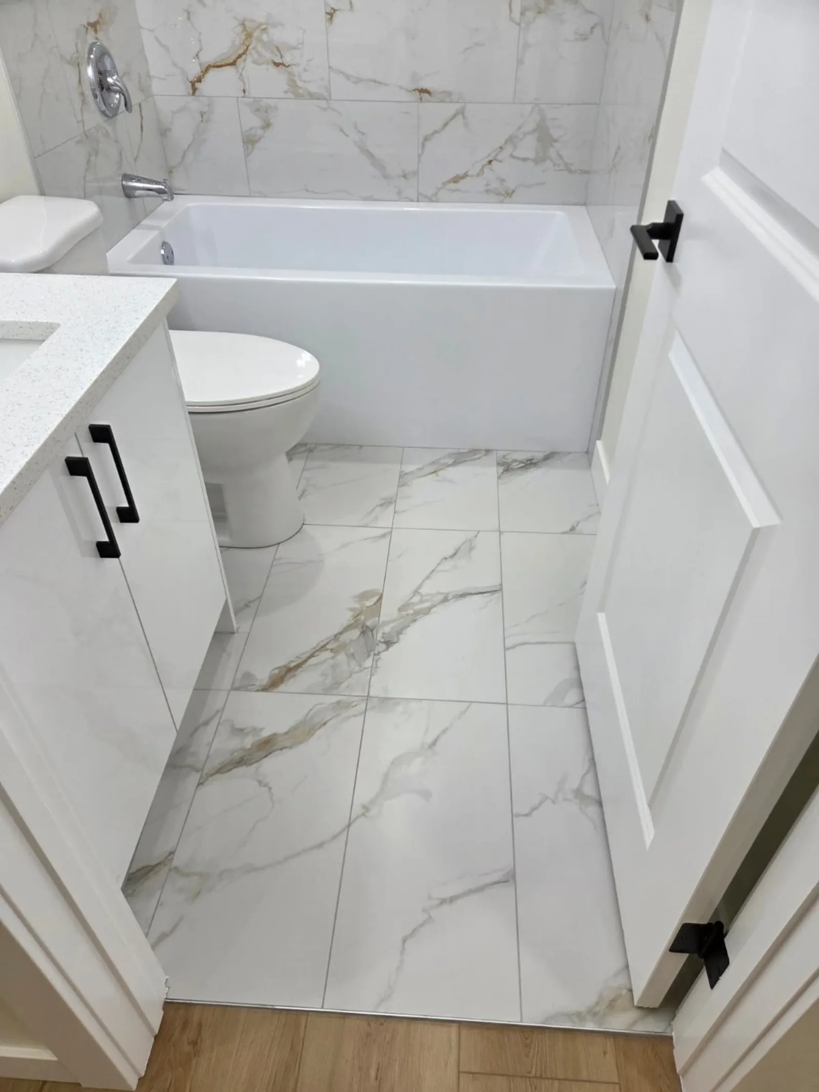 Bathroom with soaker tub, toilet and vanity on marble-look tile flooring — Calgary