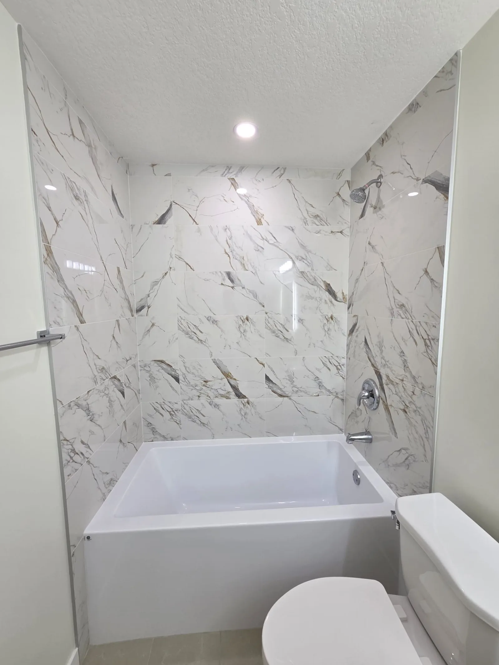 Bathroom with floor-to-ceiling marble-look tile tub and shower surround — Calgary