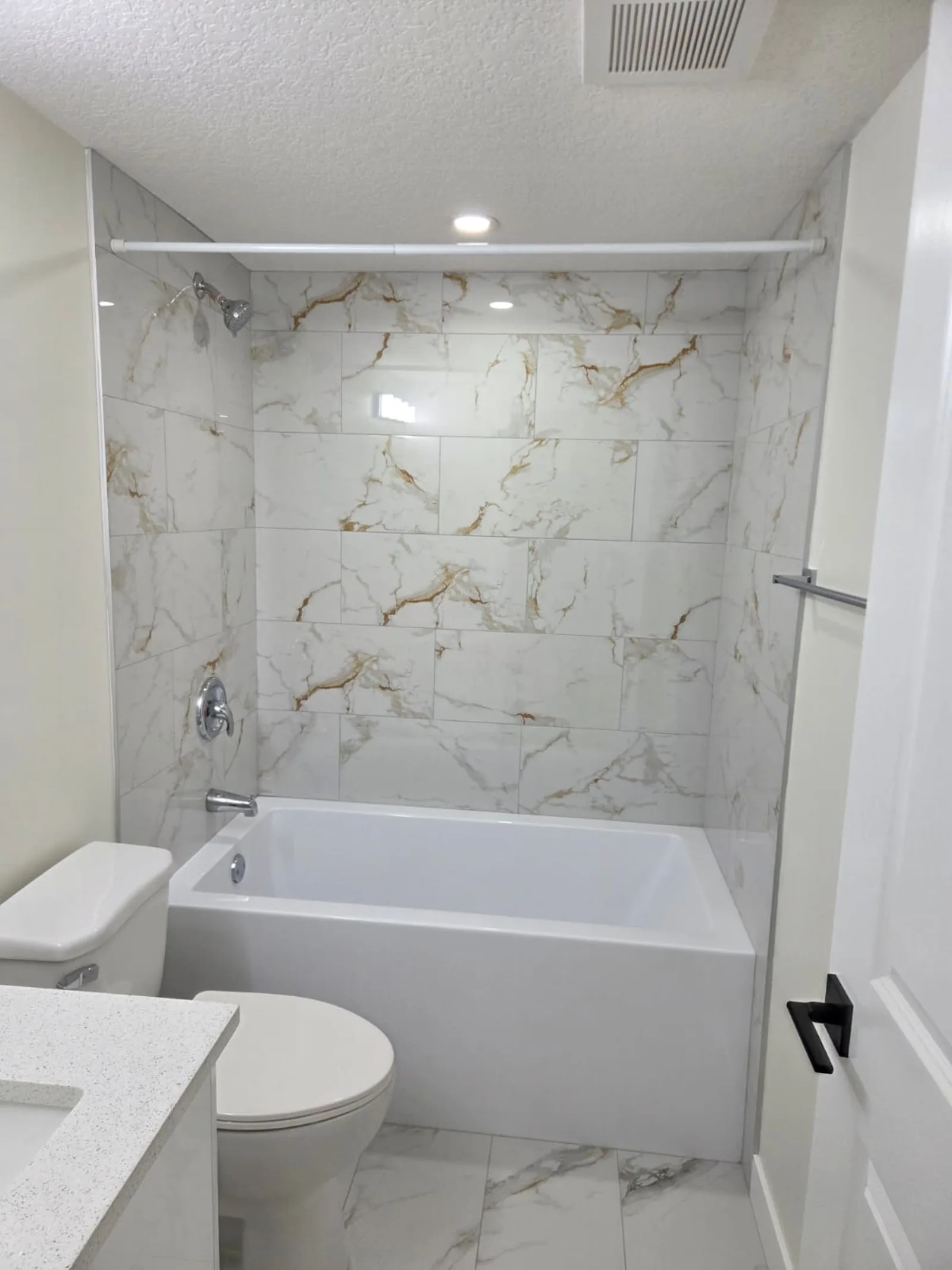 Soaker tub with marble-look tile surround in a Calgary basement suite bathroom
