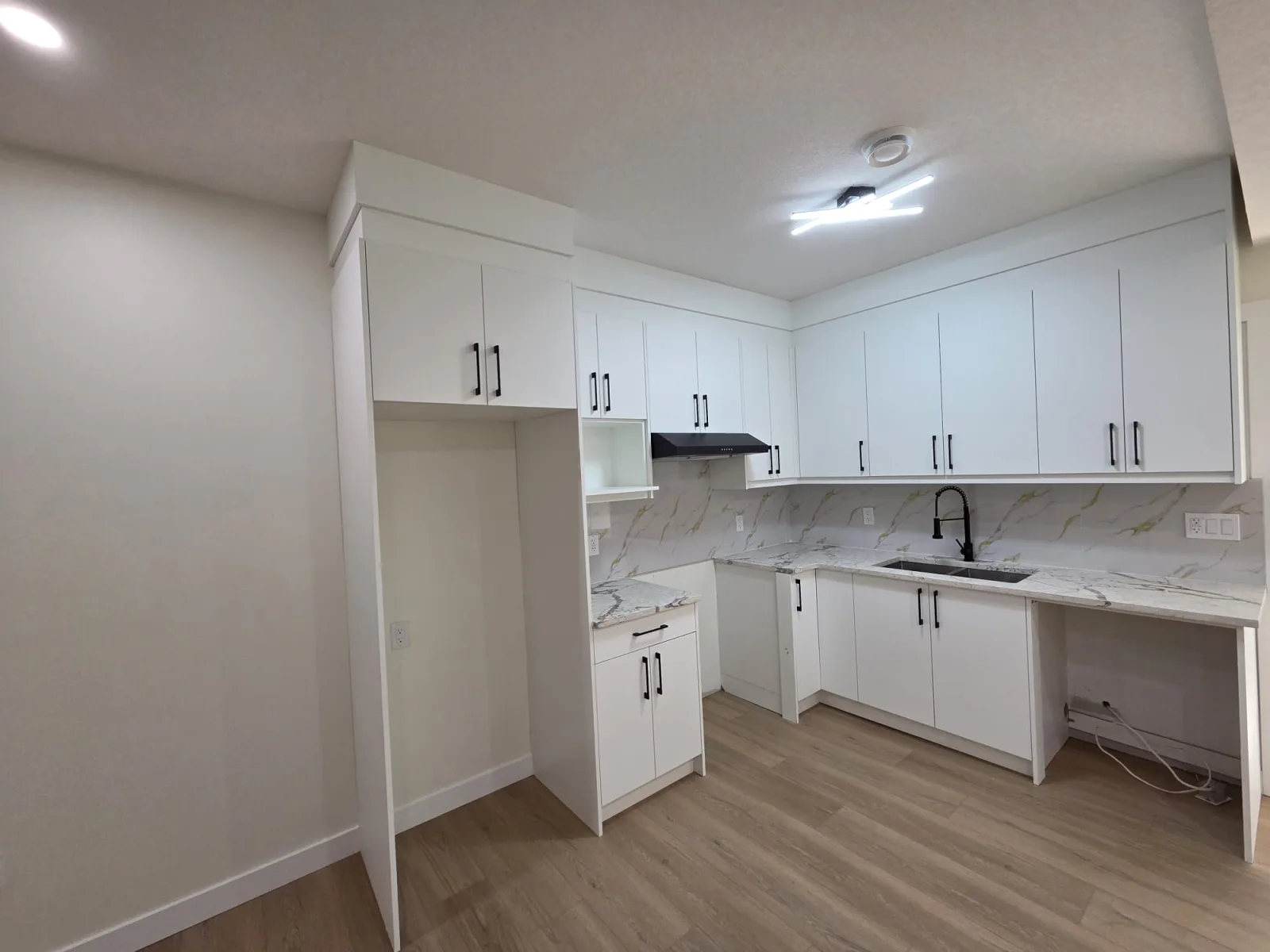 White kitchen with marble-look backsplash and built-in desk nook — Calgary secondary suite