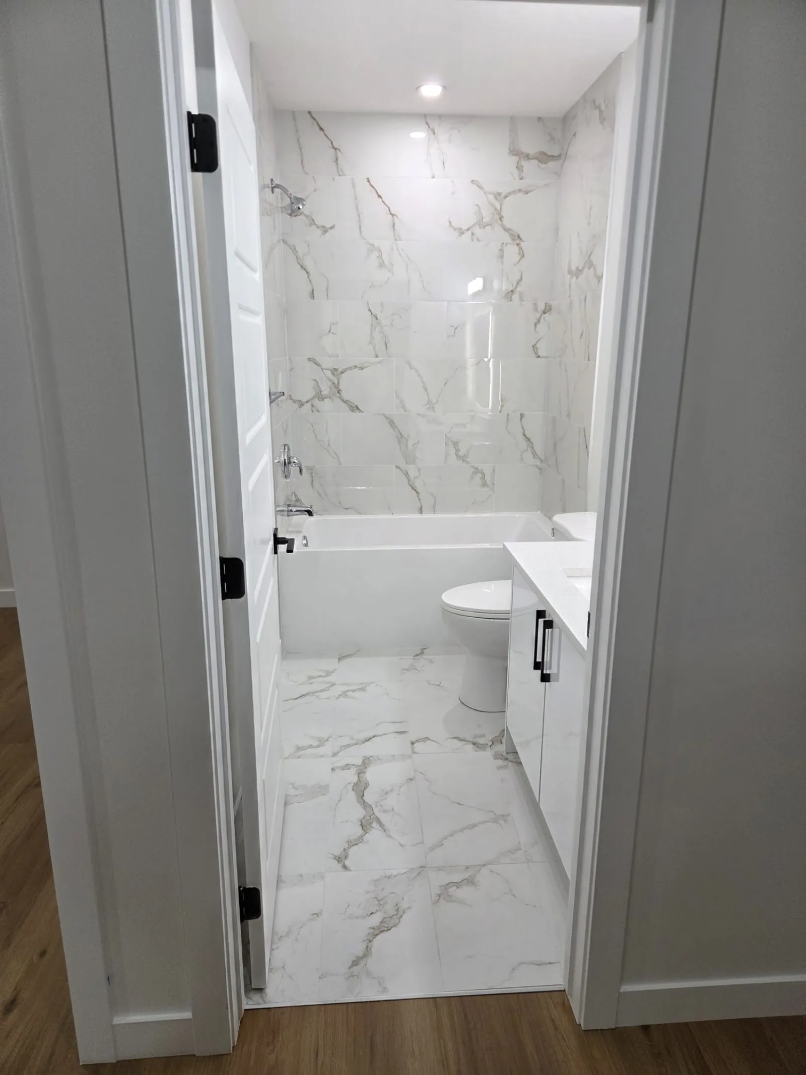 Bathroom with marble-look tile and soaker tub — Calgary basement suite