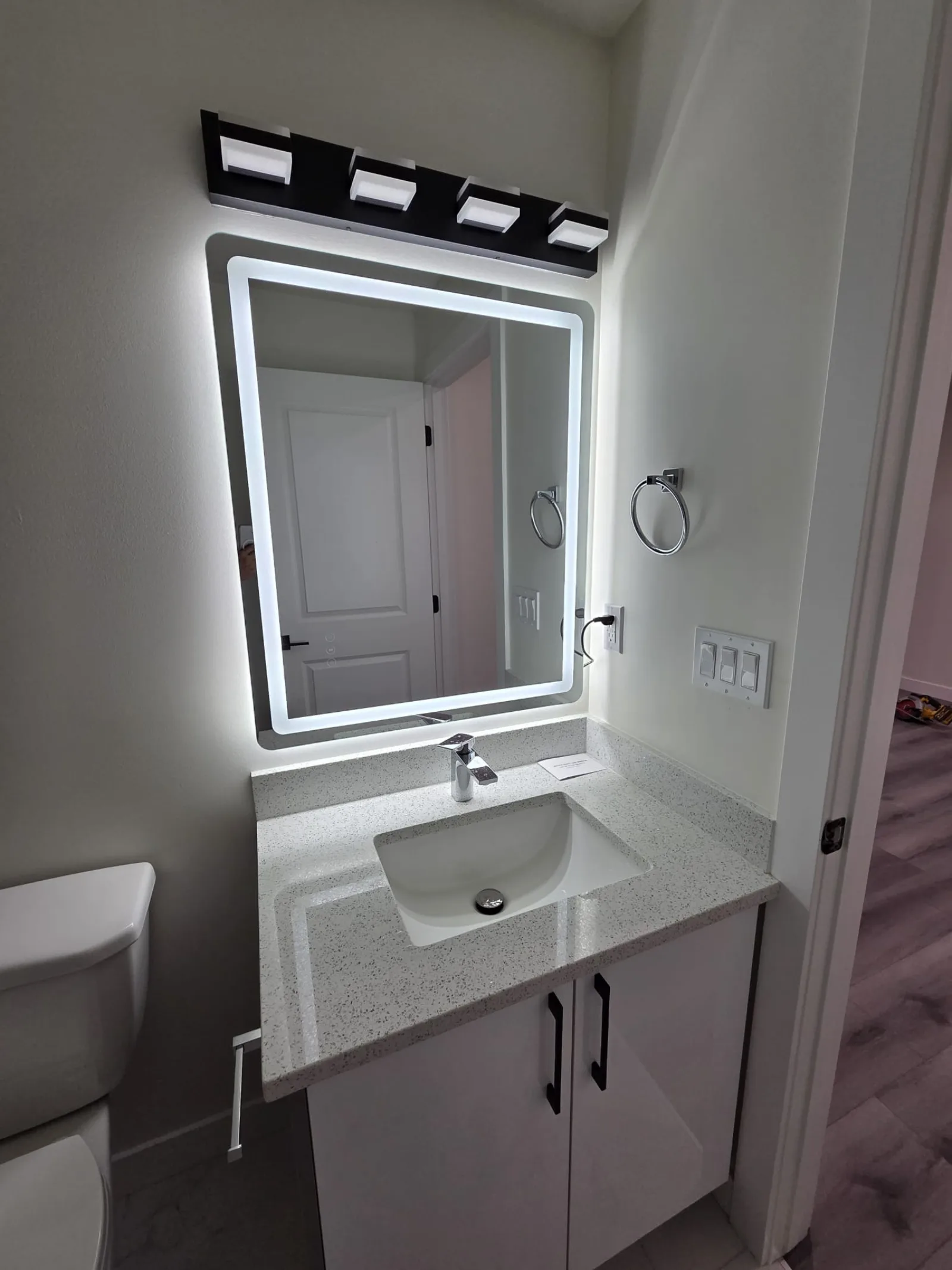 Bathroom vanity with backlit mirror over a quartz-top vanity — Calgary