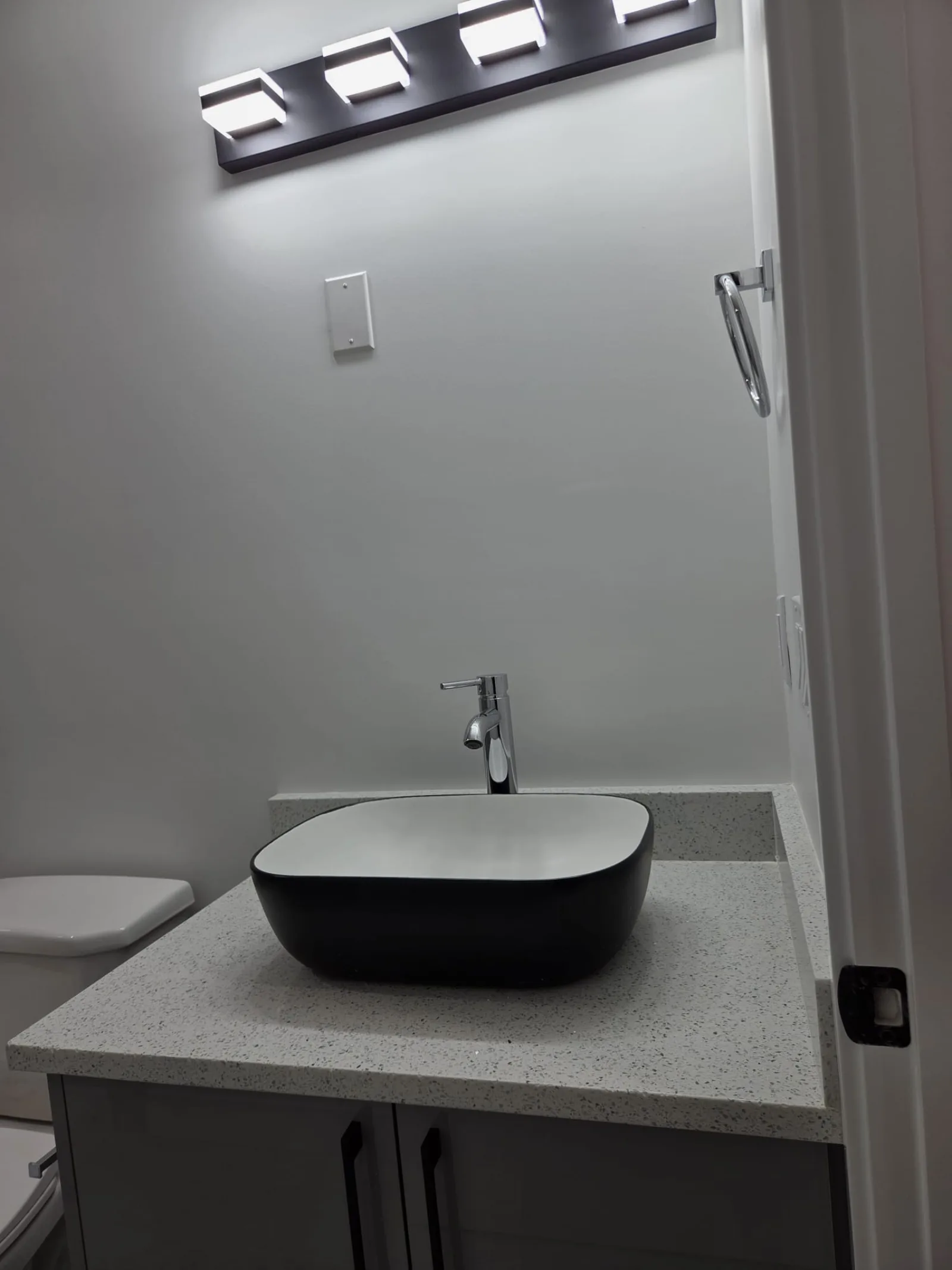 Bathroom vanity with black vessel sink on a quartz countertop — Calgary