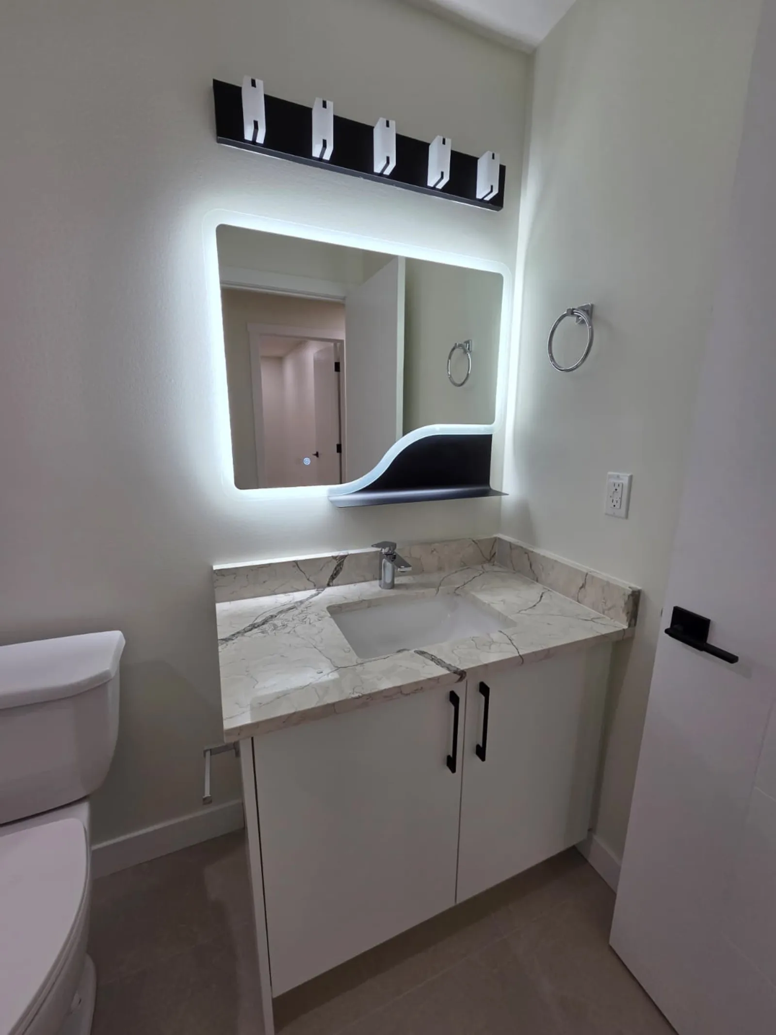 Bathroom with backlit mirror, quartz vanity and toilet — Calgary secondary suite