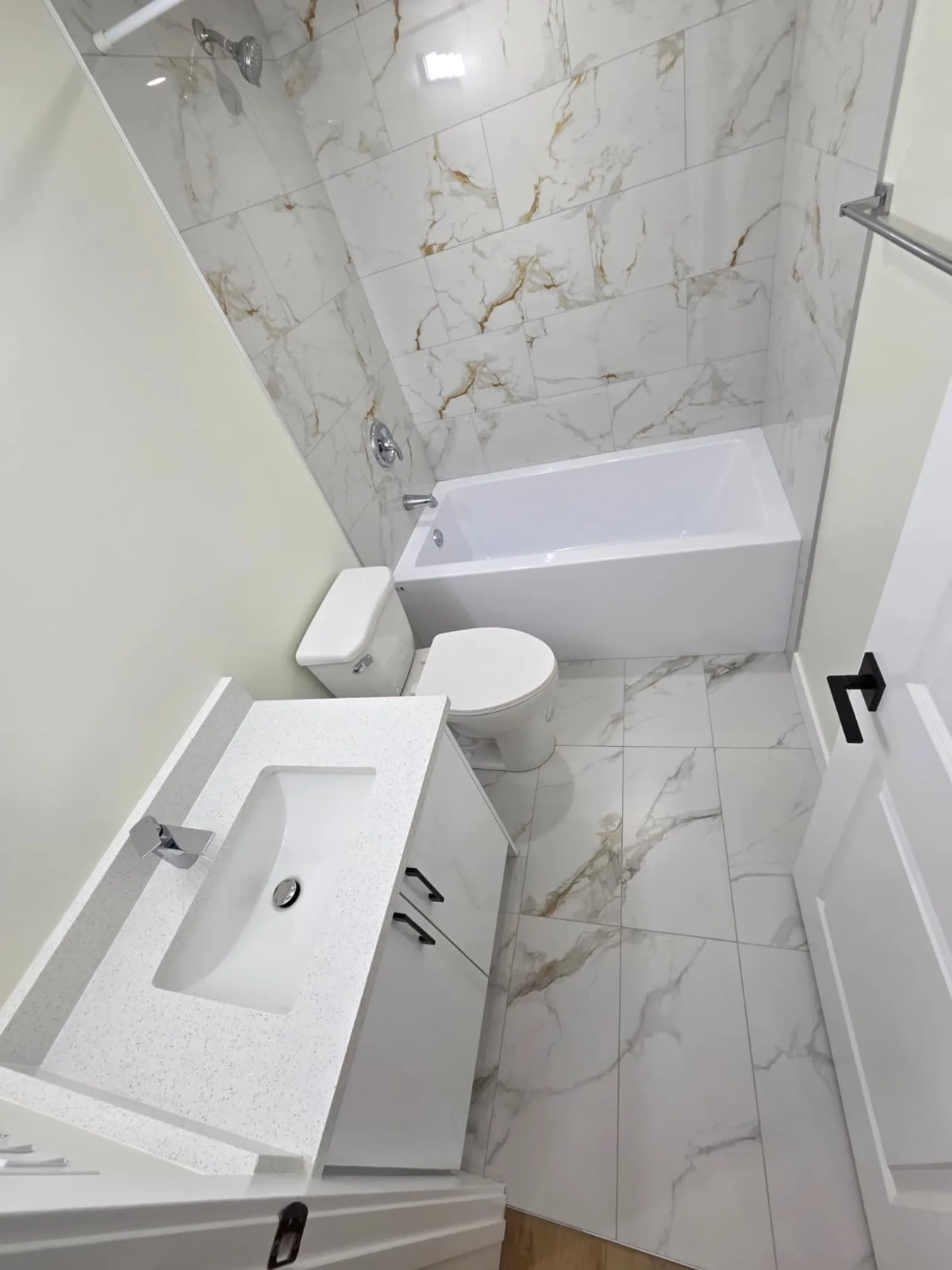 Bathroom with marble-look tile tub, toilet and vanity — Calgary basement suite