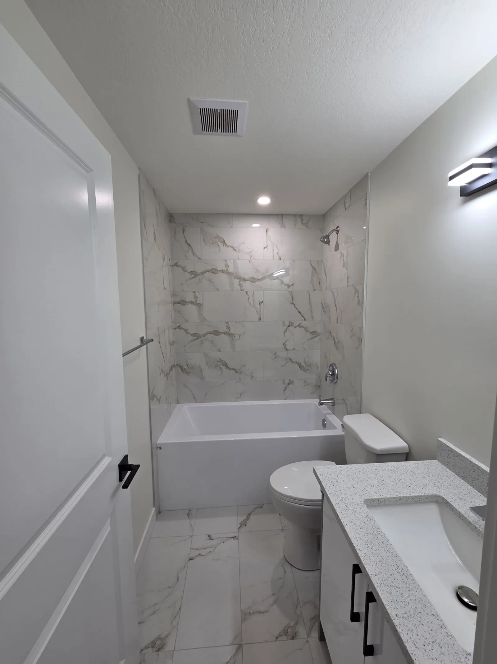Full bathroom with marble-look tile tub surround and modern vanity — Calgary secondary suite