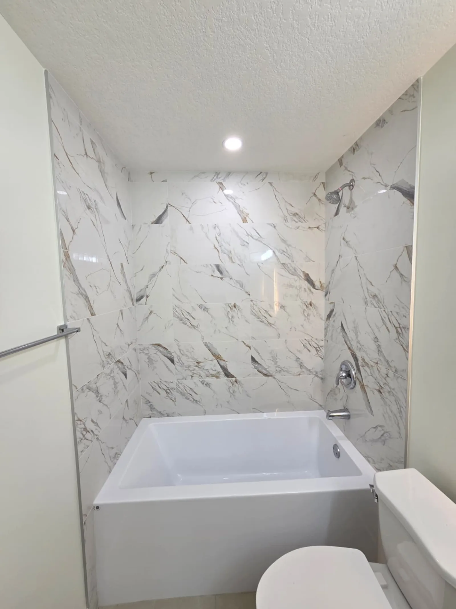 Soaker tub with marble-look tile surround in a Calgary secondary suite bathroom