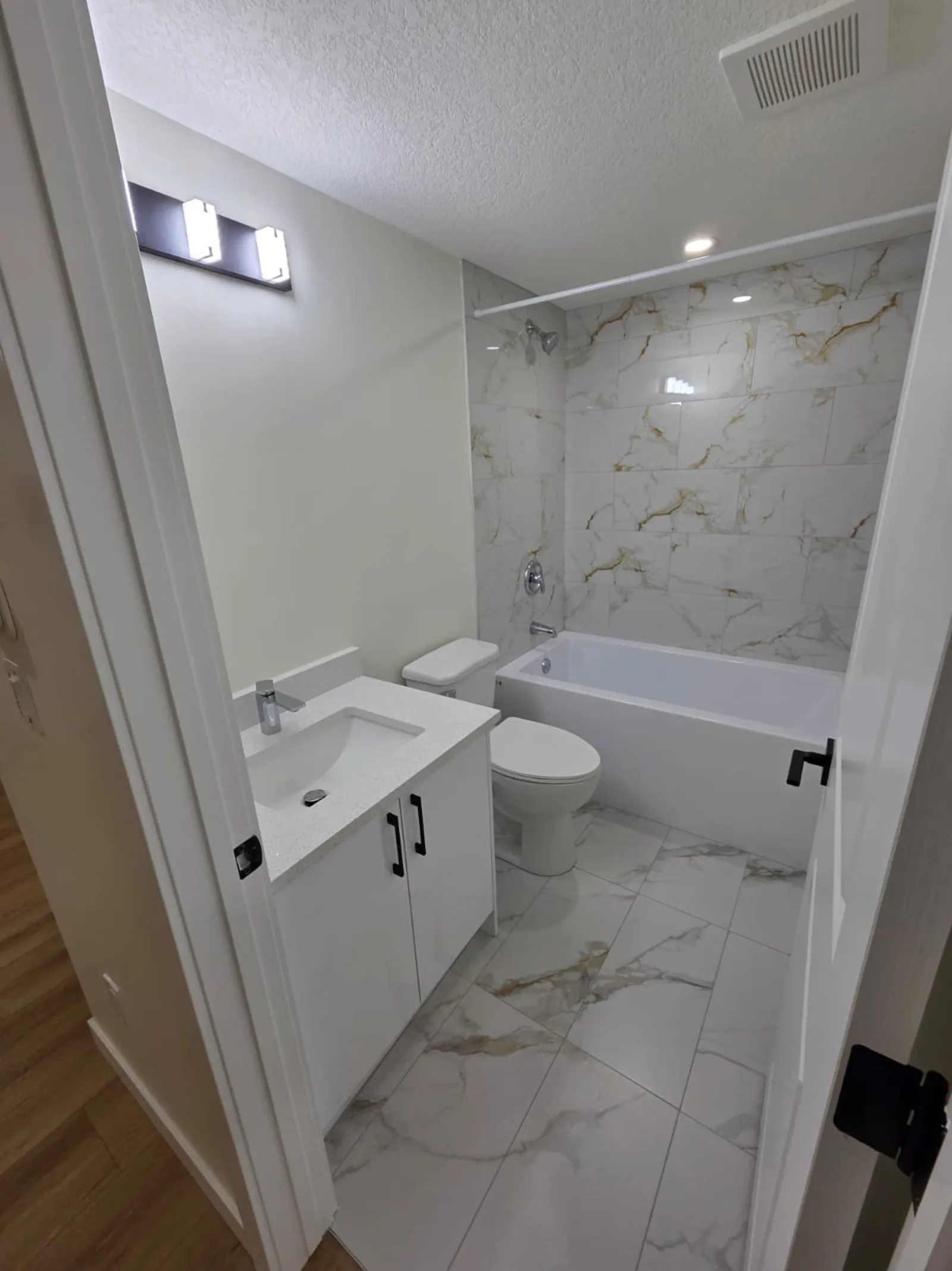 Bathroom with marble-look tile tub surround and modern vanity — Calgary suite