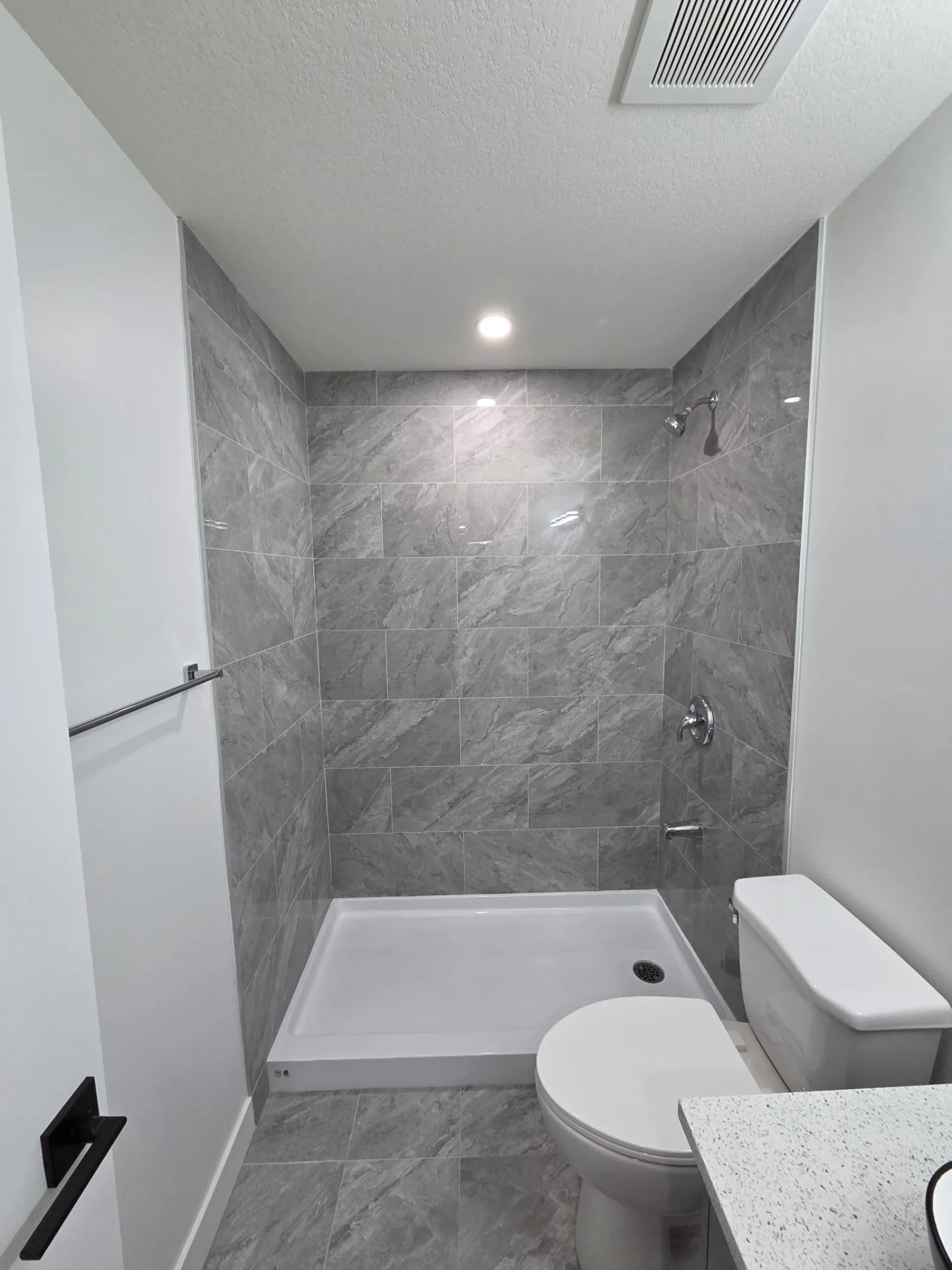 Walk-in shower with grey tile and glass surround — Calgary bathroom renovation