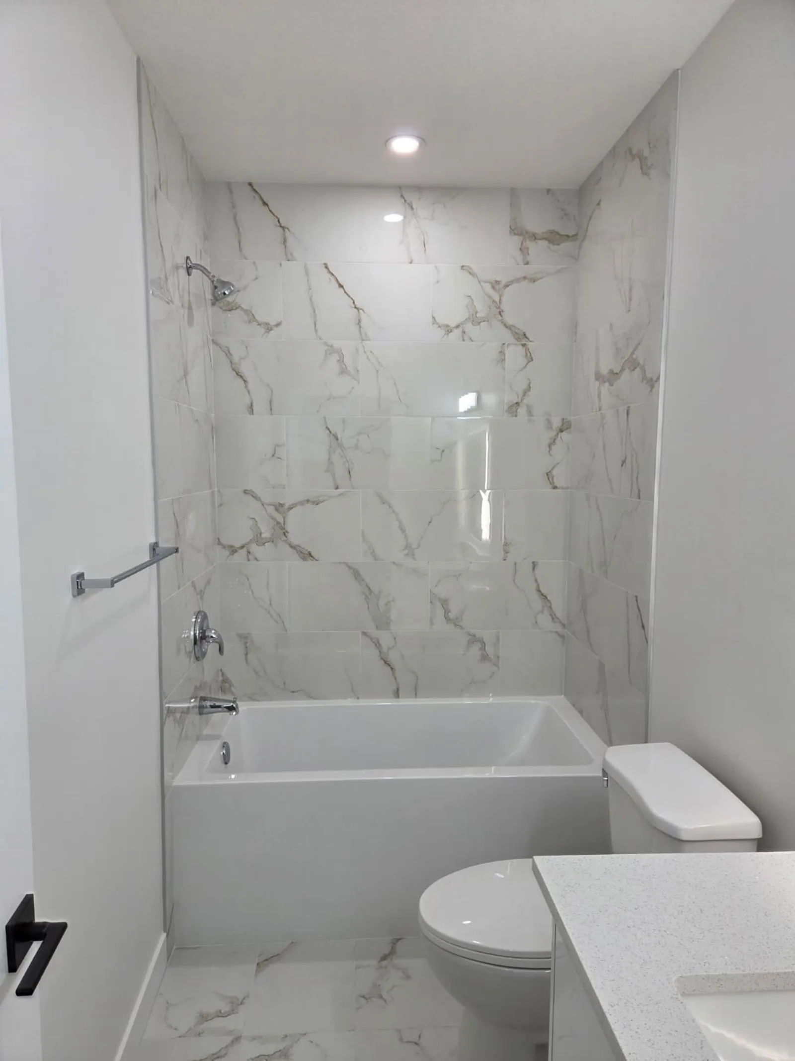 Bathroom with marble-look tile tub surround and toilet — Calgary suite