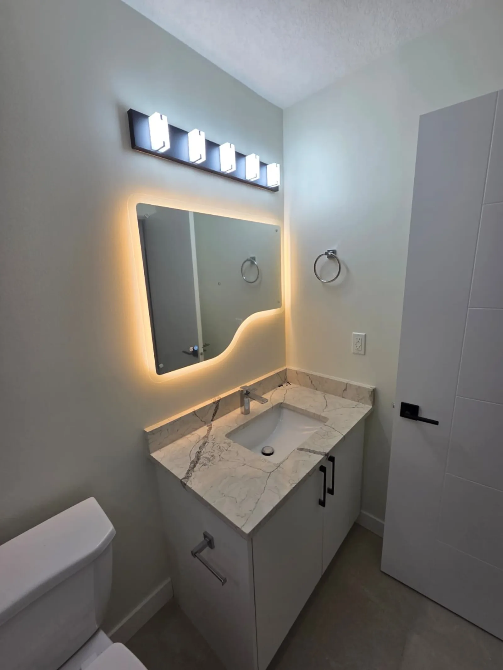 Modern bathroom vanity with backlit mirror and quartz countertop — Calgary