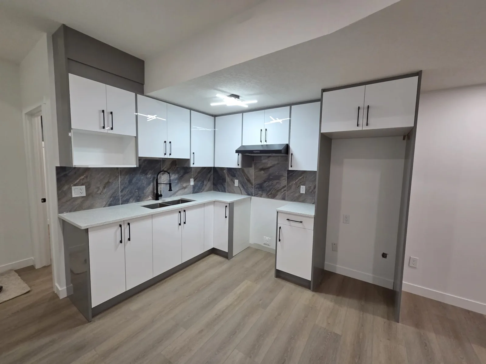 Two-tone white-and-grey kitchen with marble-look backsplash and quartz peninsula — Calgary secondary suite